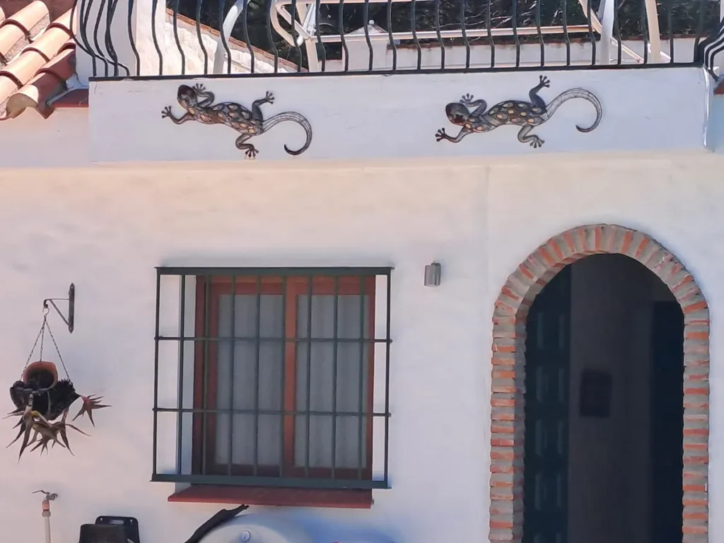 White casita door with an arched entrance and gecko wall decorations