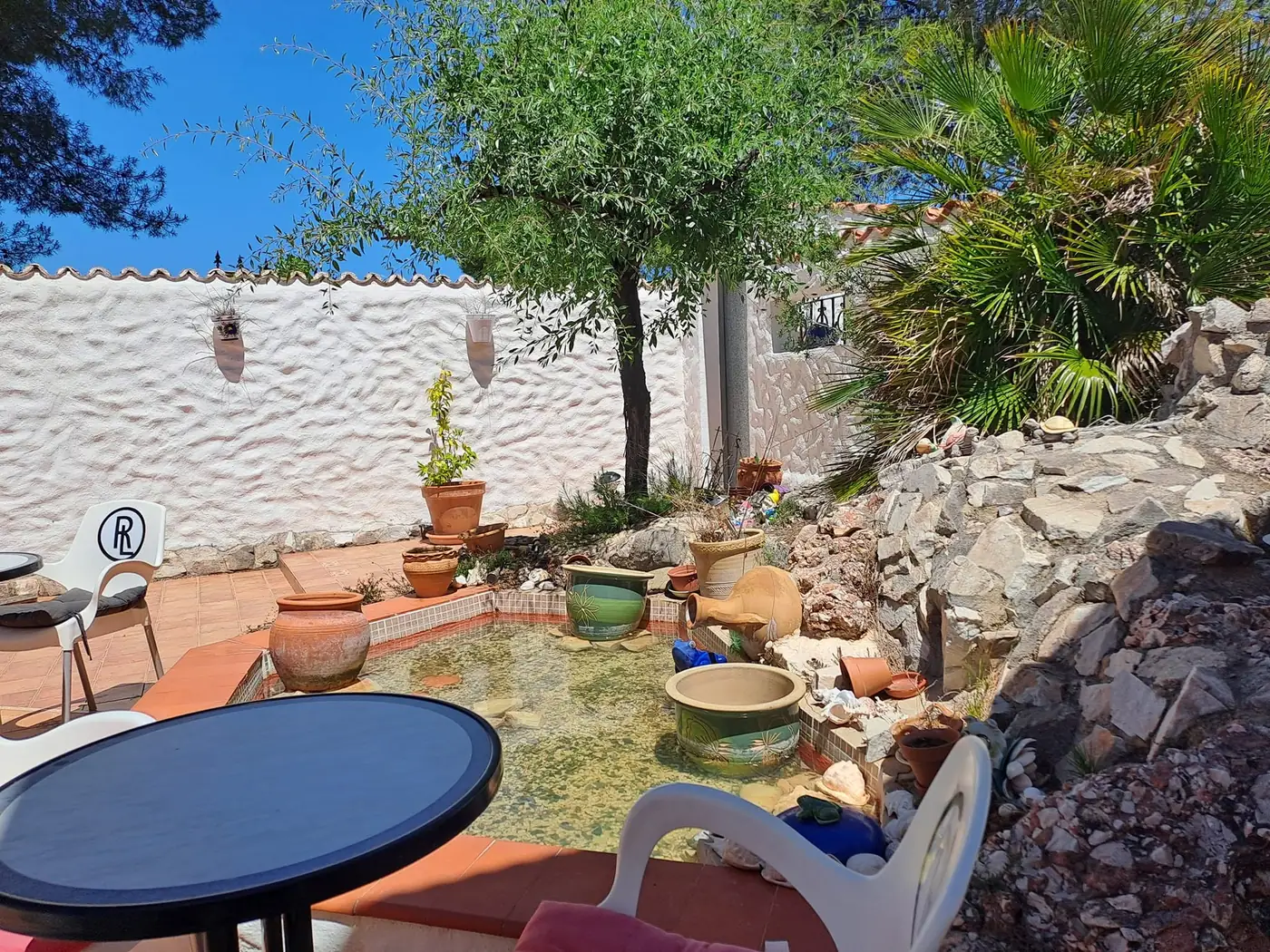 Courtyard with potted plants, a small round table and white walls