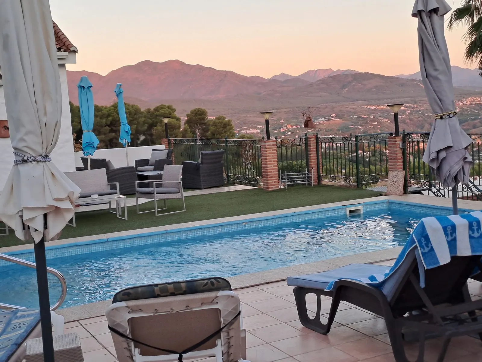 The pool terrace with sun loungers and the mountains in golden evening light